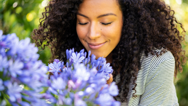A woman smelling fresh flowers—an example of tangible appreciation ideas that engage the senses and leave a lasting impression.